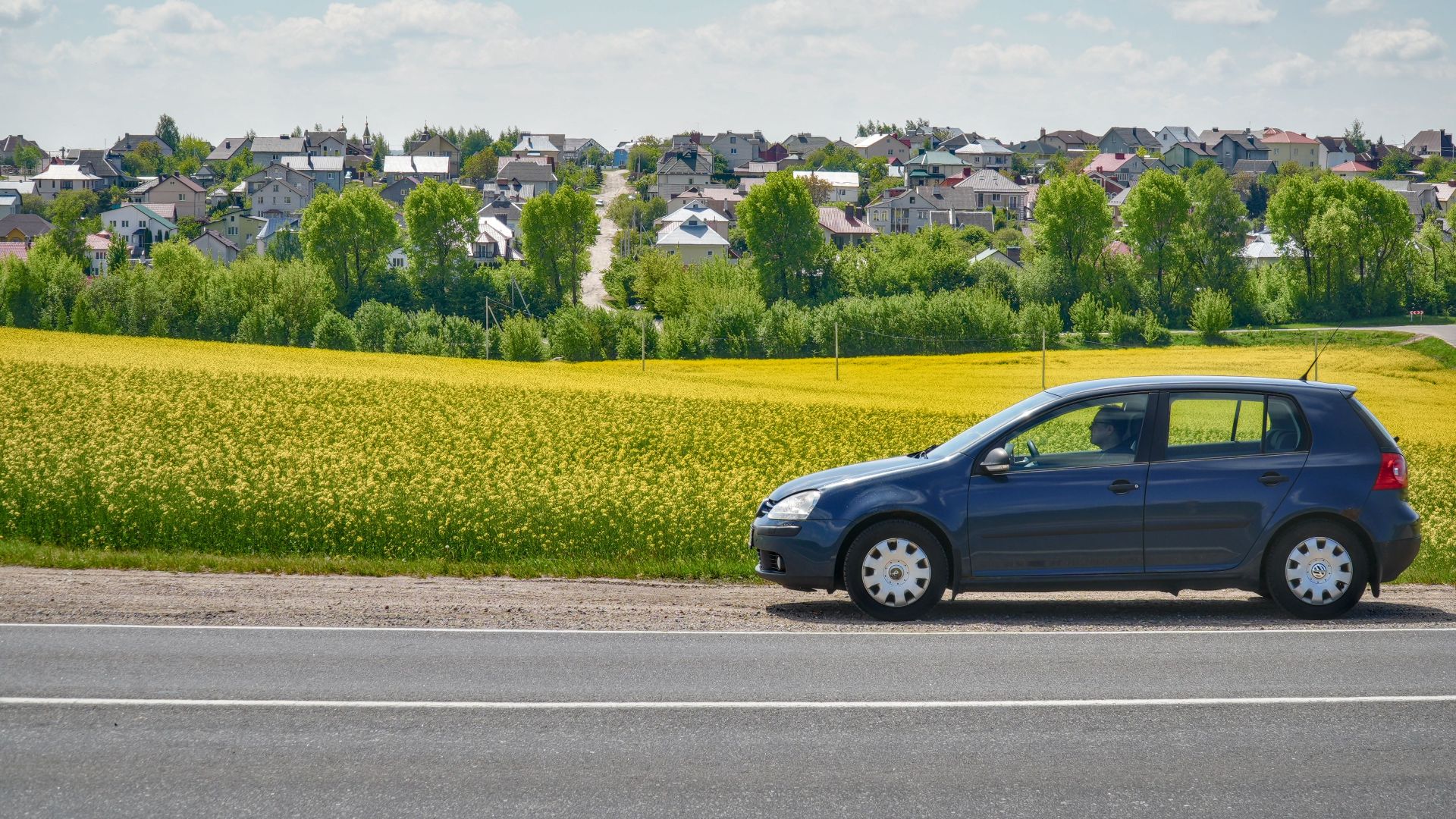 A lone car parked by a country road with a picturesque rural landscape in Grodno Region, Belarus.
