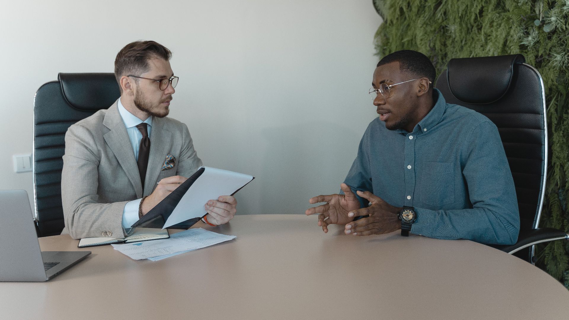 Two businessmen engaged in a discussion during a job interview in a contemporary office environment.