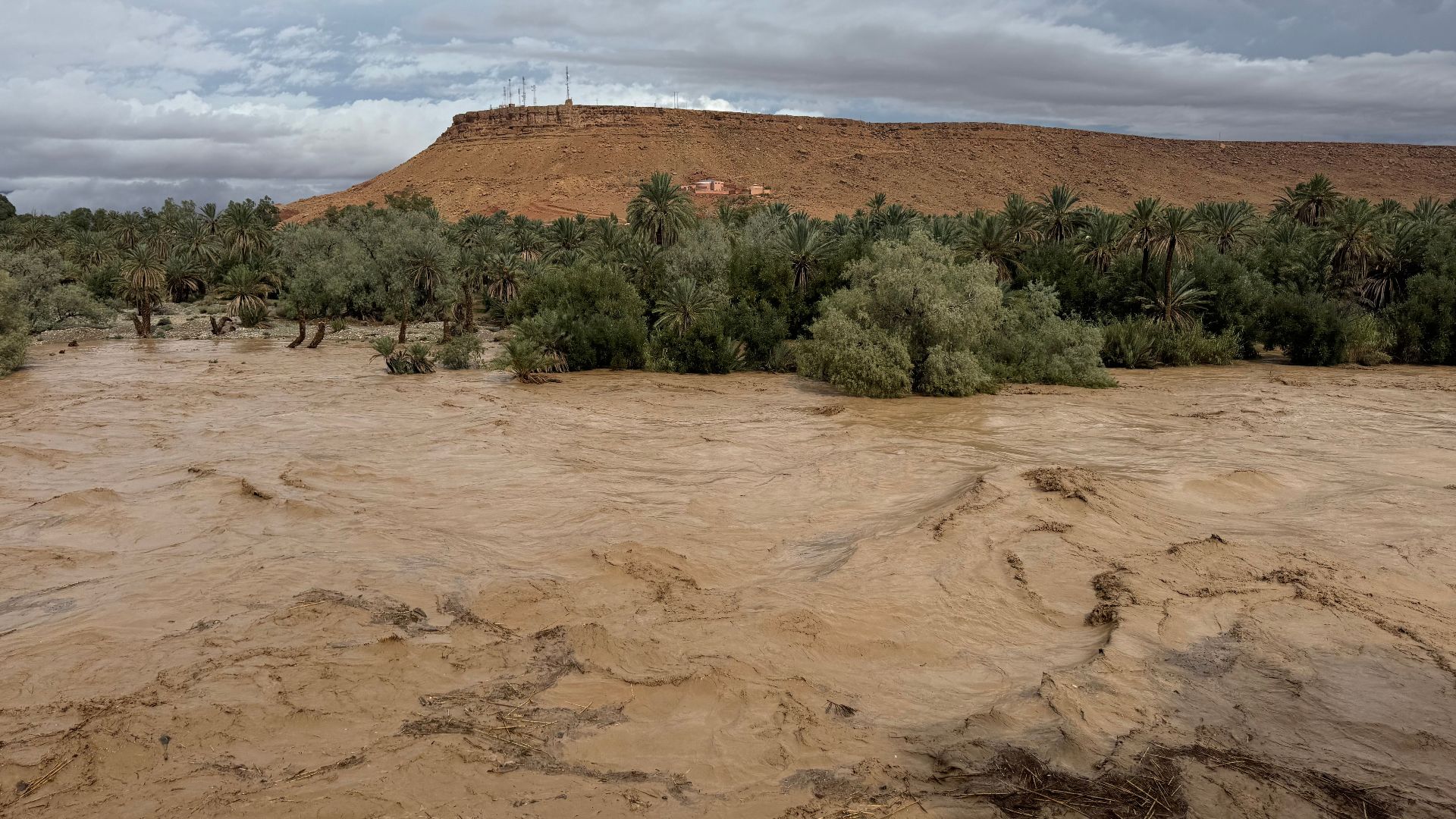 A dramatic flood event in Morocco showcasing nature's power with rushing waters and lush surroundings.