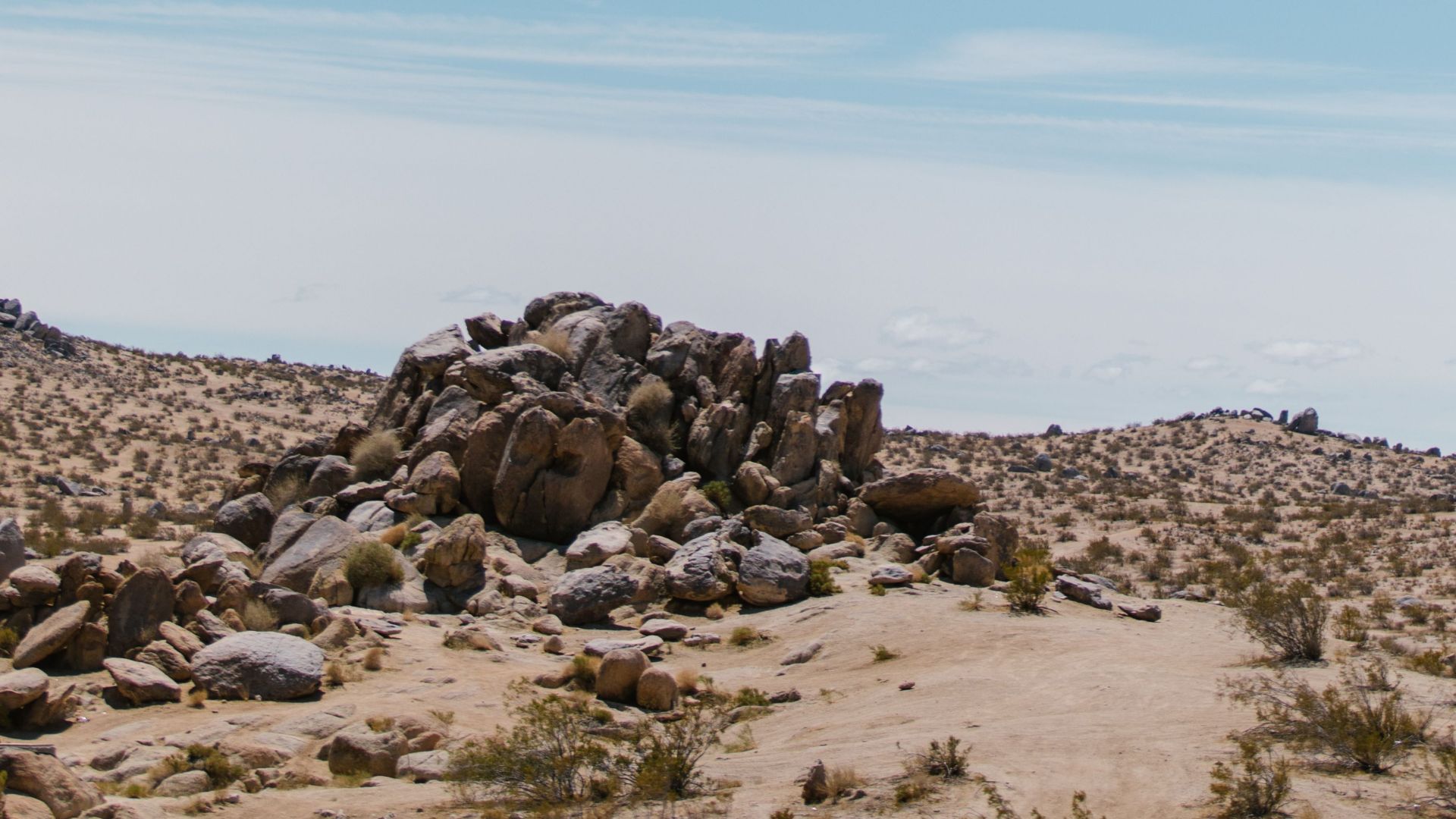 Serene desert landscape featuring a pile of rocks under a vast clear blue sky.