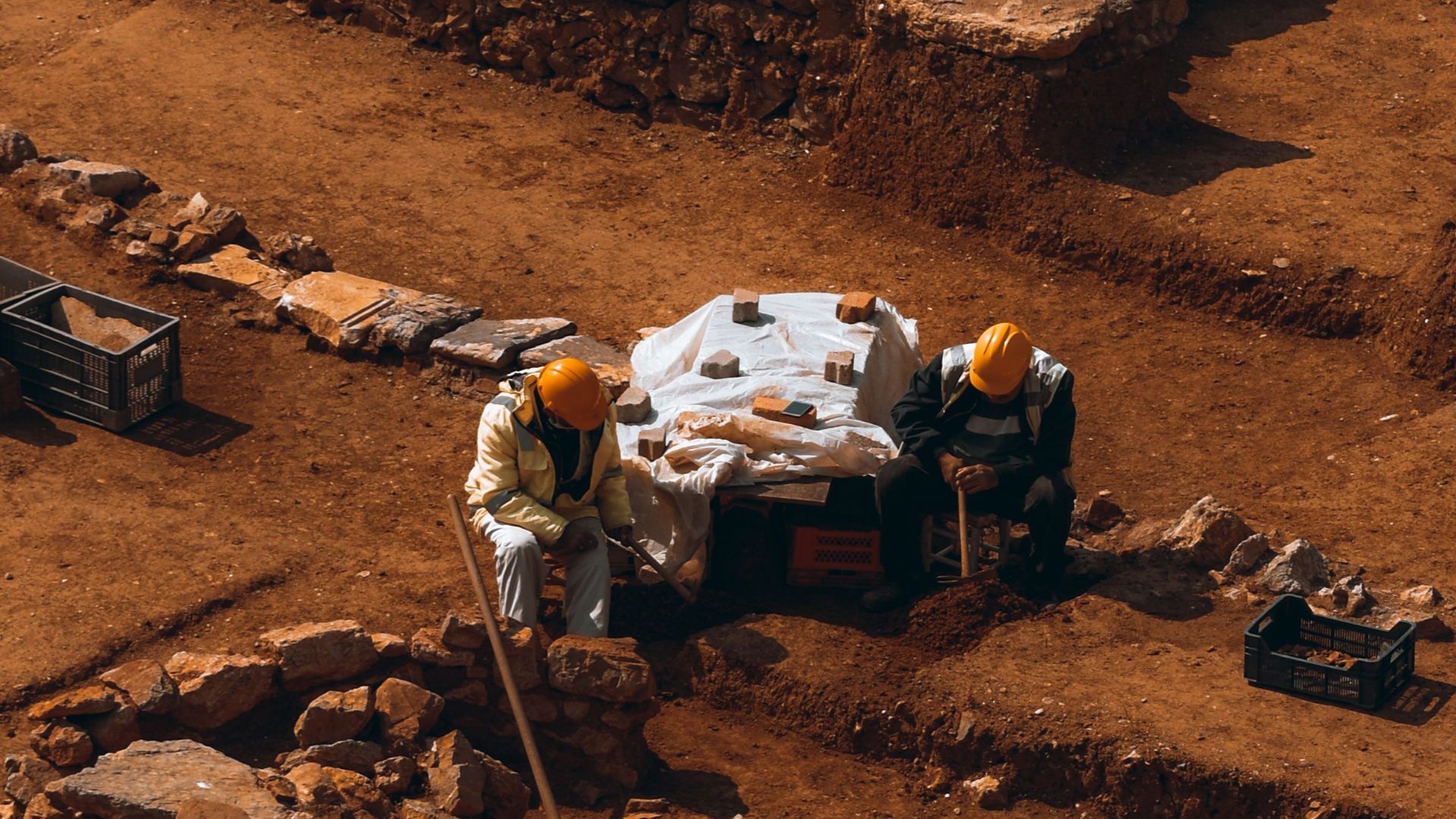 Workers in orange helmets at an archaeological excavation site in Istanbul, Turkey among ancient ruins.