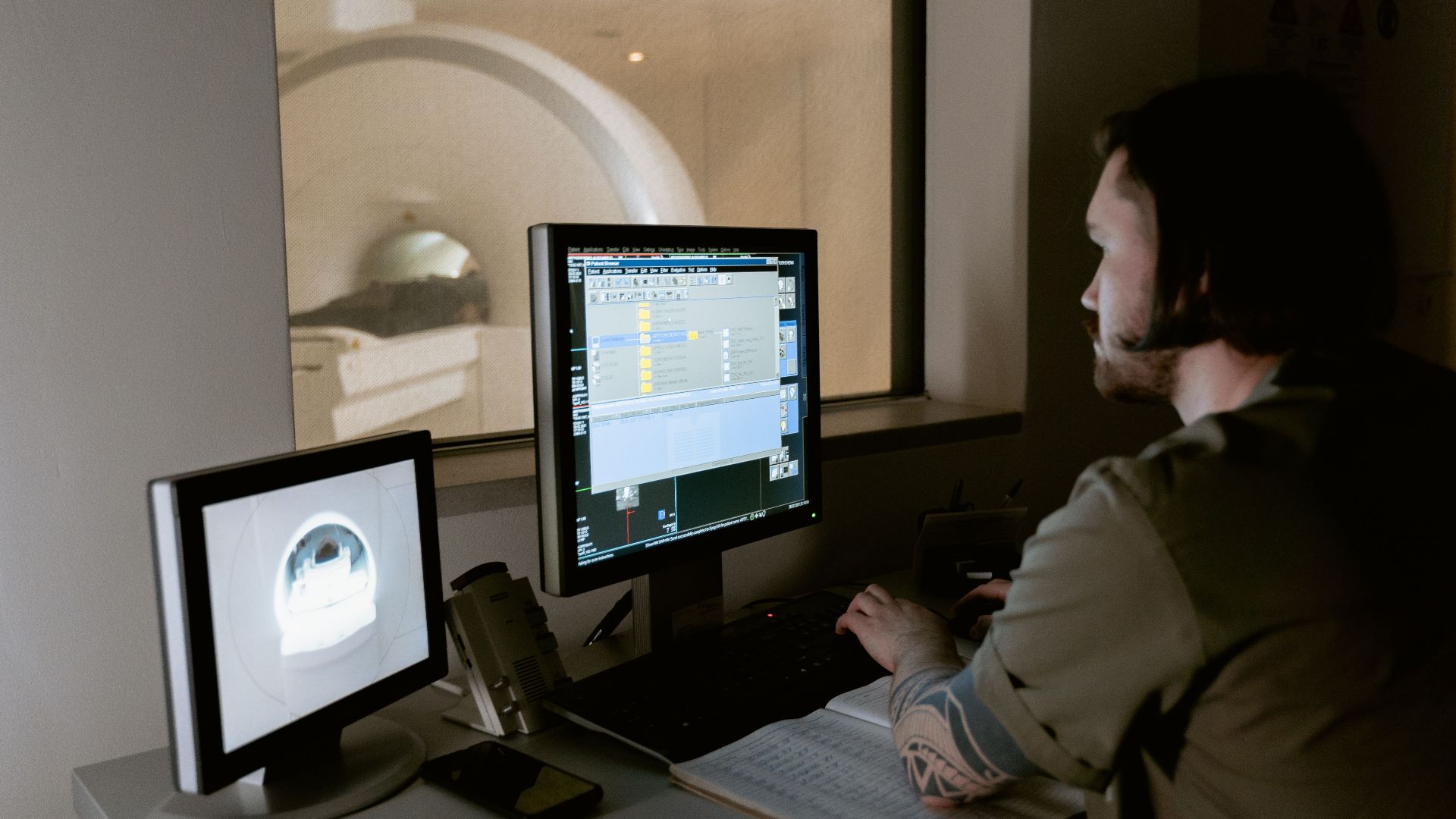 A radiologist examines MRI scan results on computer monitors in a medical facility.
