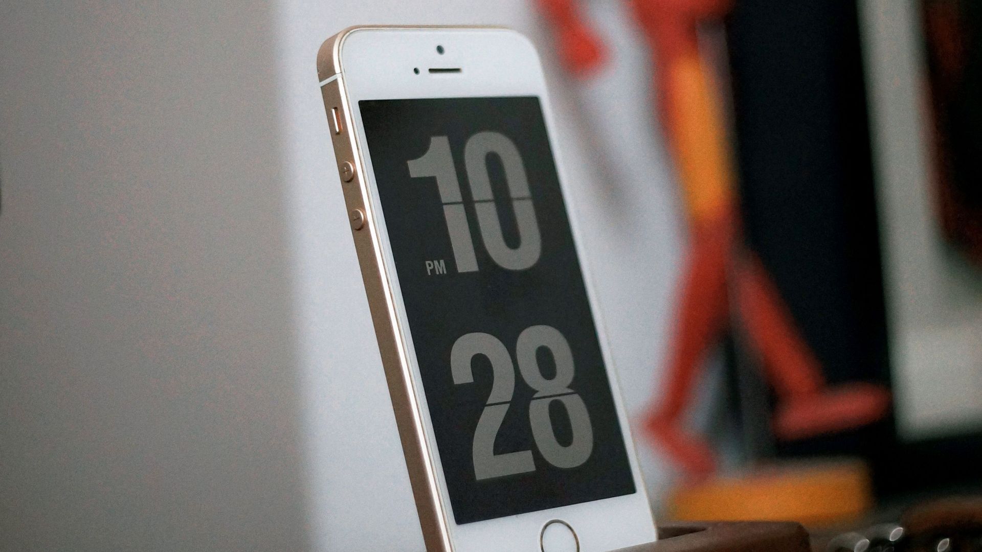 Smartphone on wooden dock with digital clock displayed, stylish home decor.