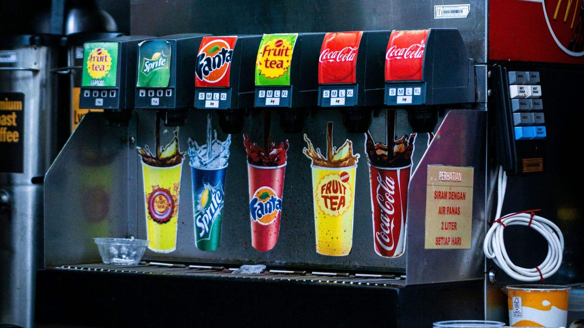 Soft drink dispenser with various soda options in fast food restaurant.