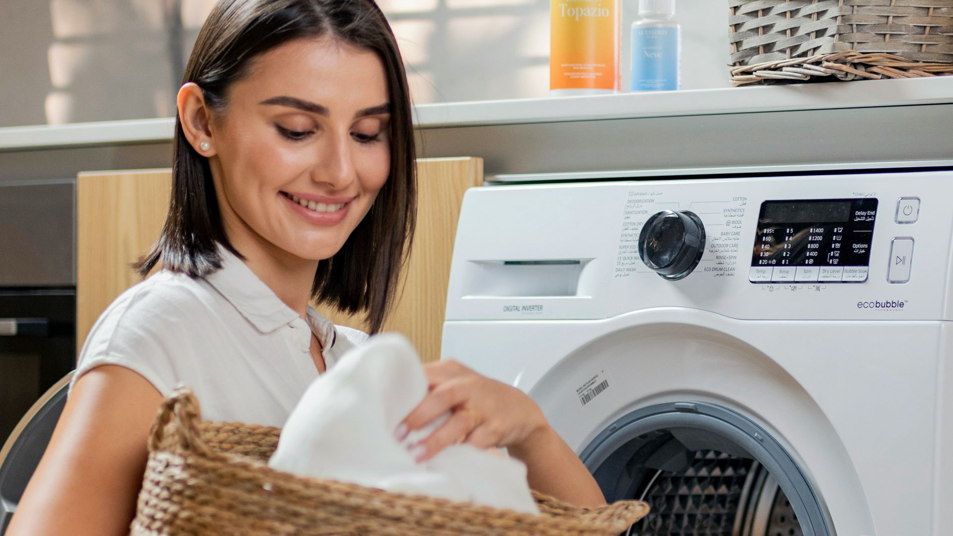 a woman is holding a basket near a washing machine