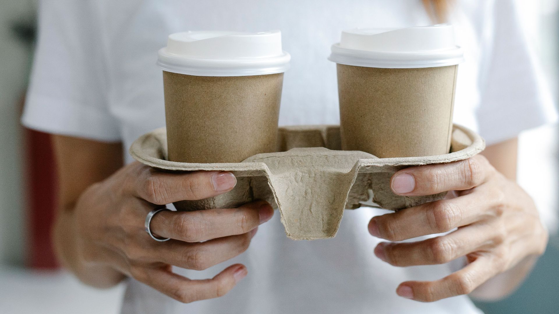 Soft focus of anonymous female carrying paper cups of takeaway coffee during break