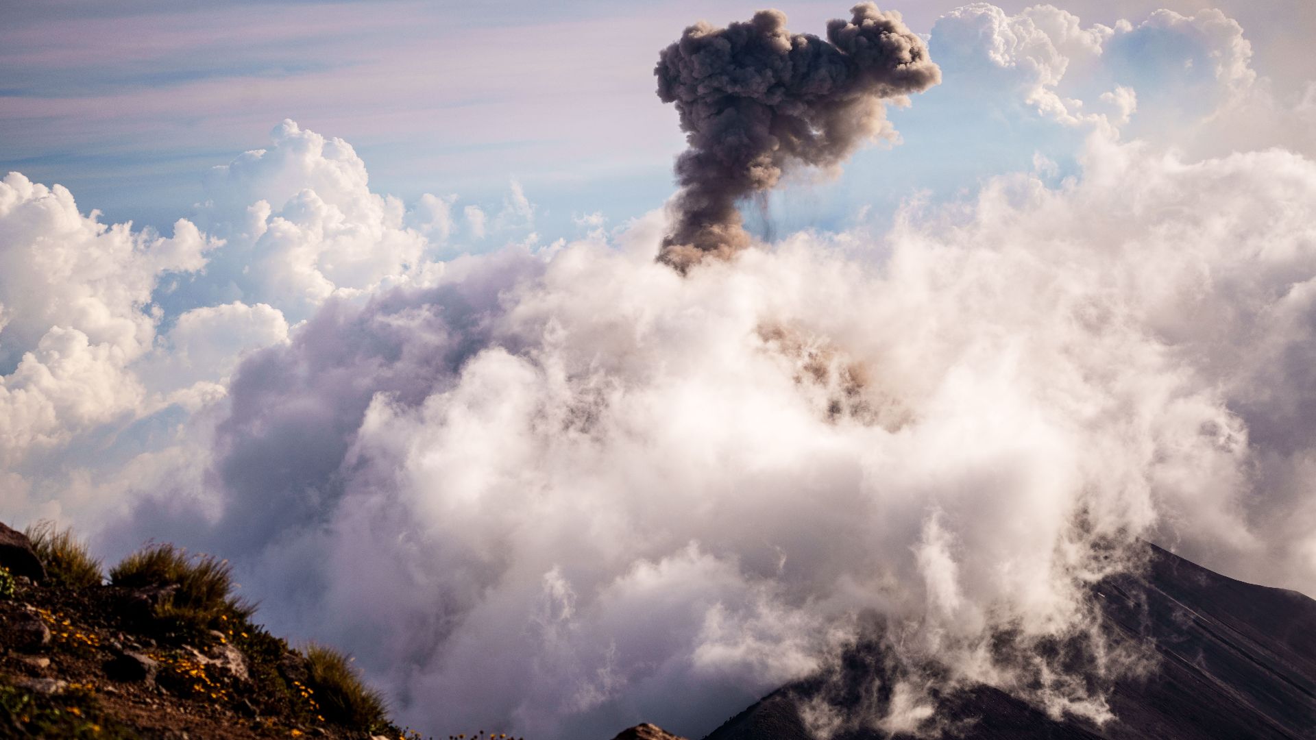 Stunning view of Volcán de Fuego erupting, showcasing clouds and smoke in Sacatepéquez, Guatemala.