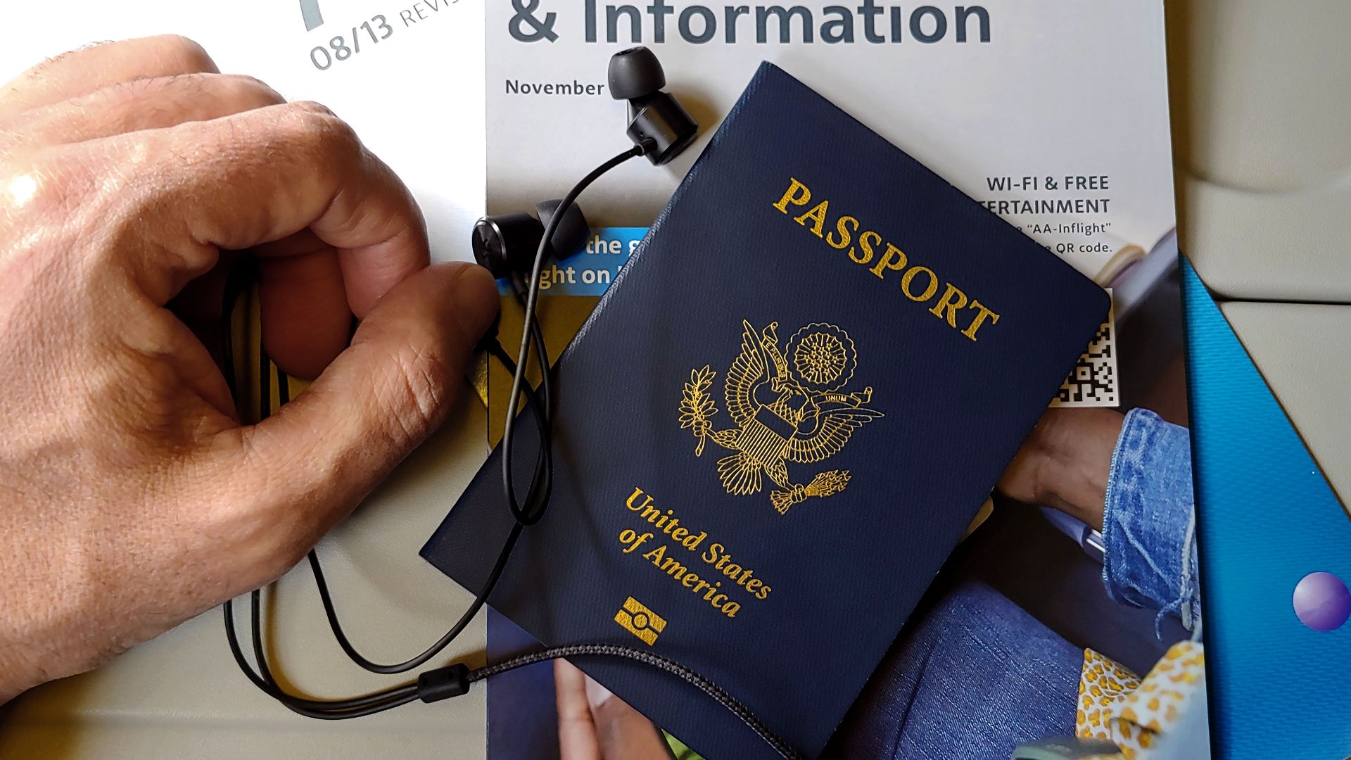 Close-up of US passport with inflight magazine and headphones on an airplane seat, ready for travel.