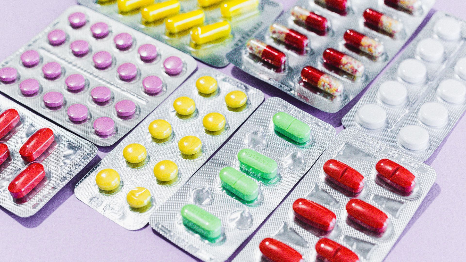 Close-up of various colorful pills in blister packs, showcasing diverse medicine types.