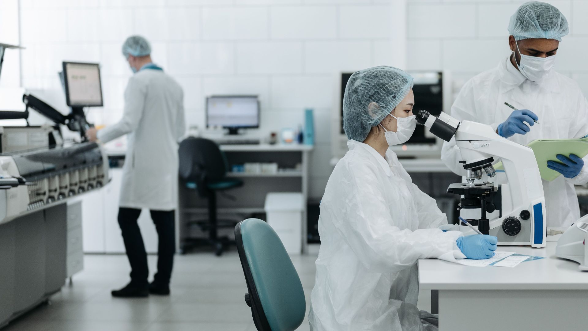 Researchers in protective gear examining samples in a state-of-the-art laboratory setting.