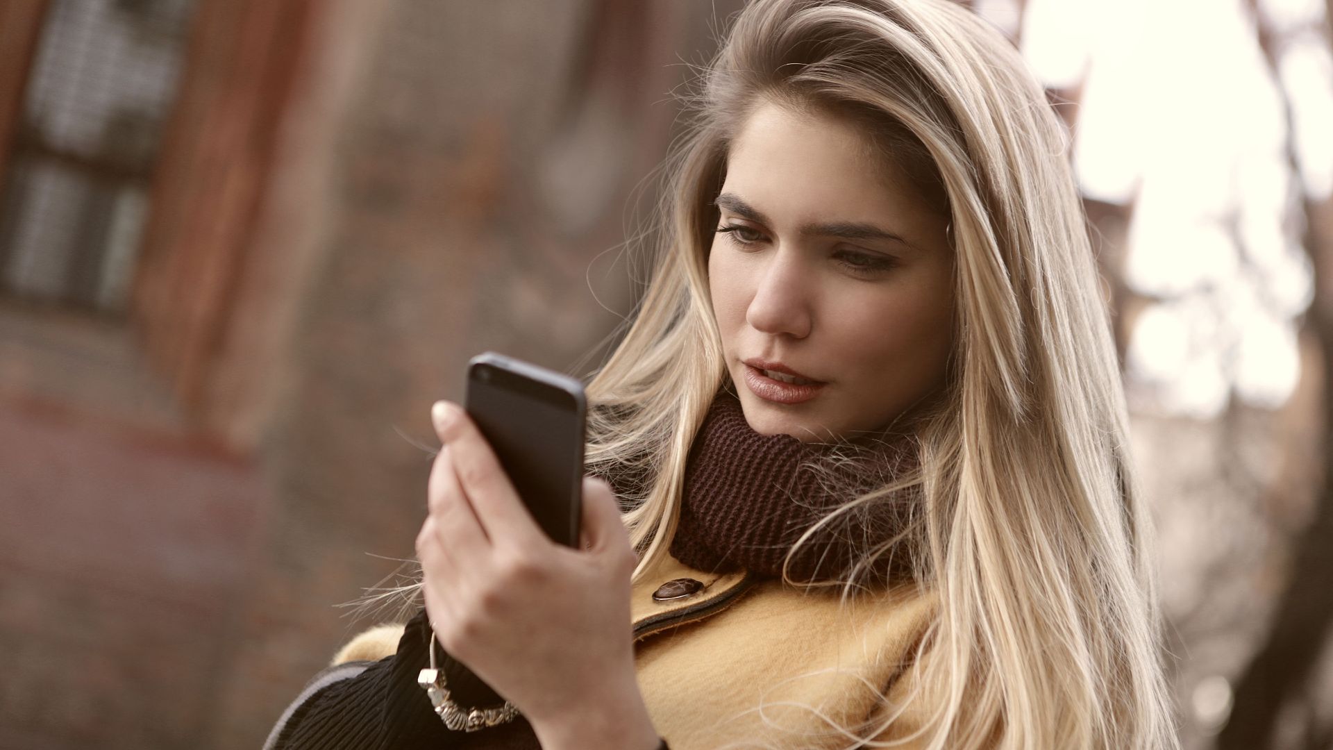 Young woman in autumn attire using smartphone outdoors. Perfect for communication and lifestyle themes.