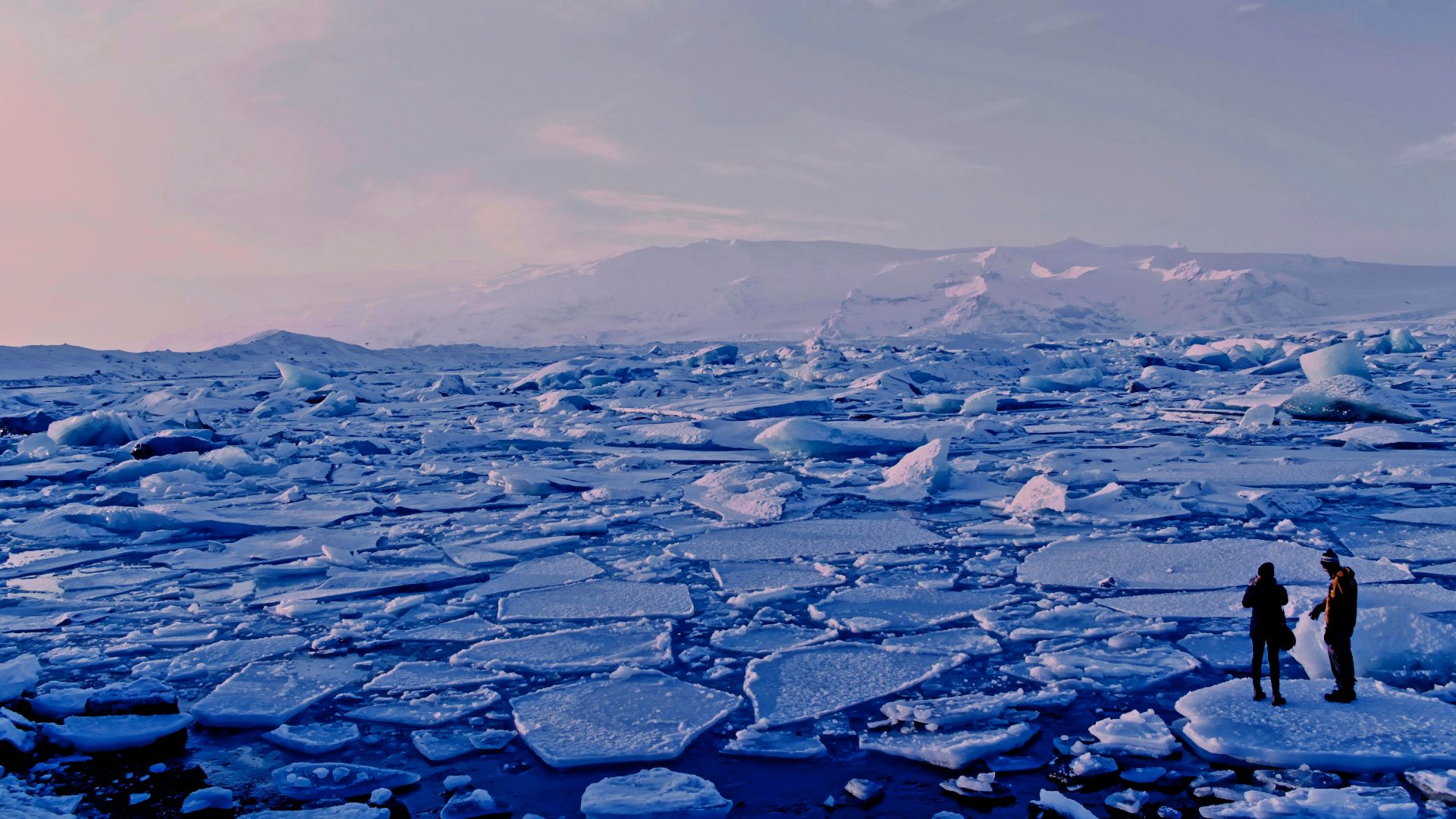 man and woman standing cracked sea ice under gray sky