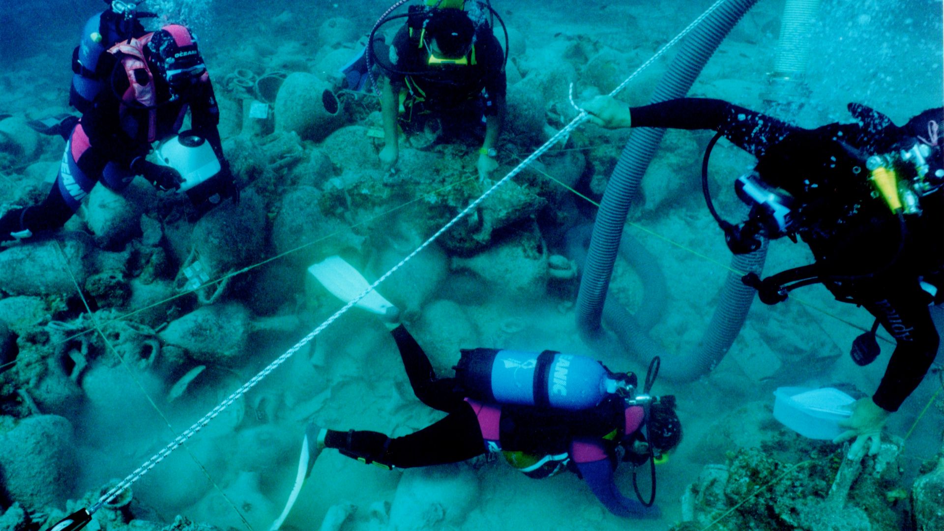 Diving archaeologists excavating the Alonnisos shipwreck in fall 2000, trench Θ3. The 2x2 m rope grid and airlift are visible.