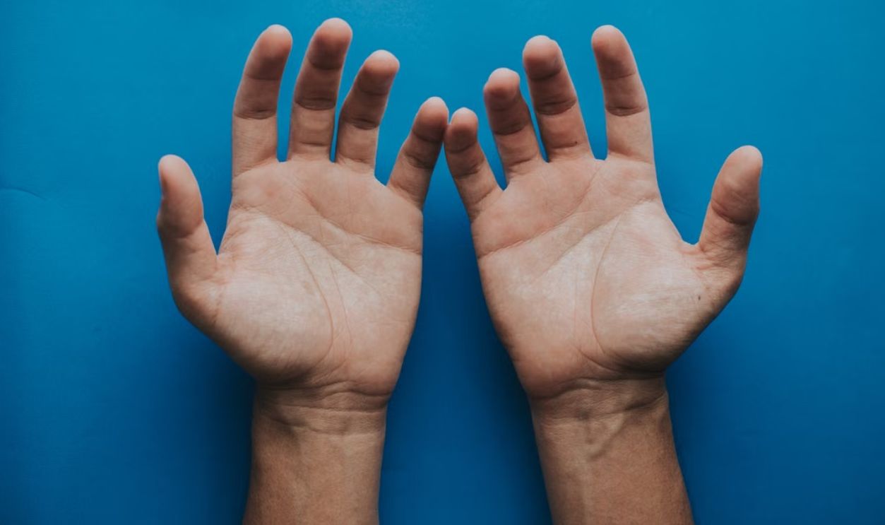 Two open hands against a solid blue background, symbolizing openness and communication