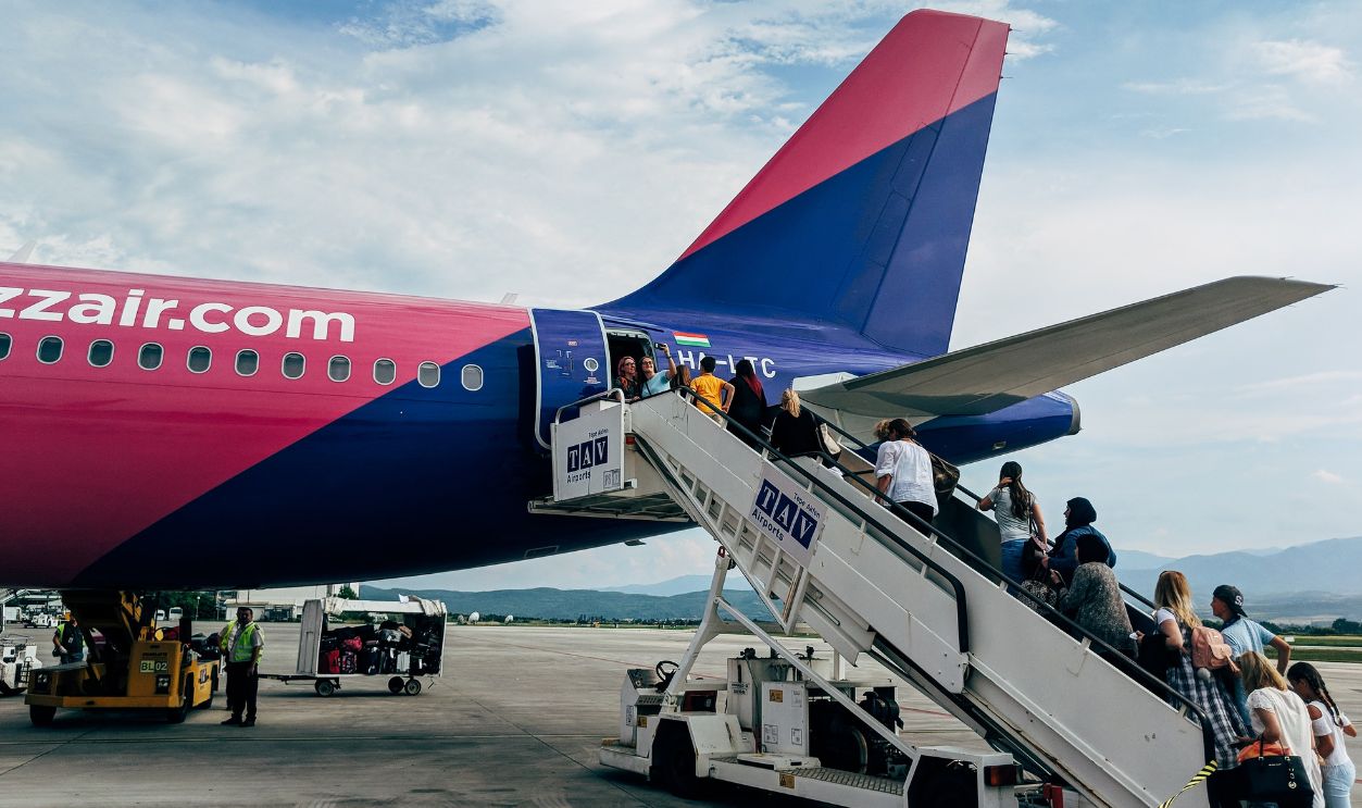 Travelers boarding a WizzAir Airbus A320 jet on a clear day at the airport