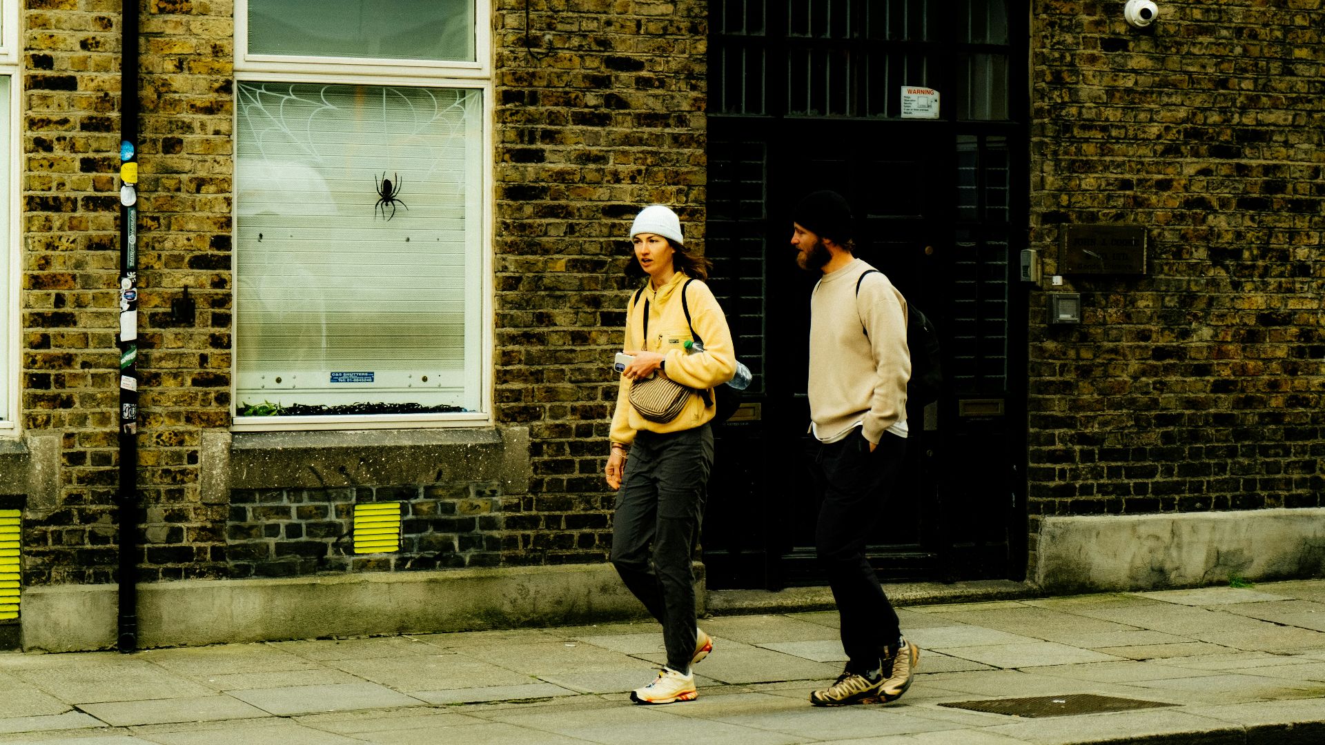 Two people walk on a city sidewalk.
