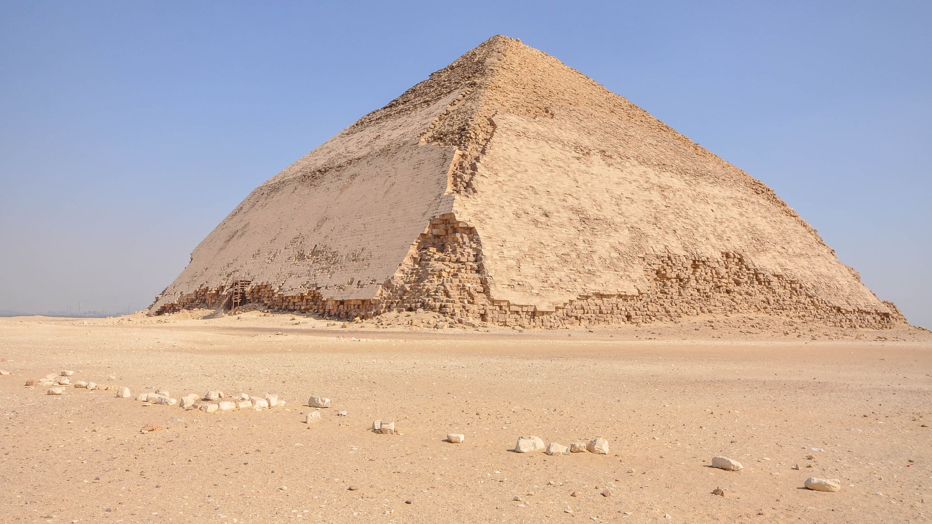The Bent Pyramid is an ancient Egyptian pyramid located at the royal necropolis of Dahshur, approximately 40 kilometres south of Cairo, built under the Old Kingdom Pharaoh Sneferu (c. 2600 BC). A unique example of early pyramid development in Egypt, this 