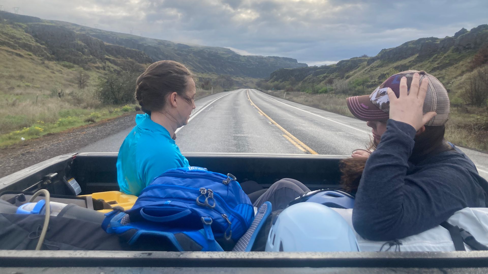 Two women in the back of a pickup truck on a rural road