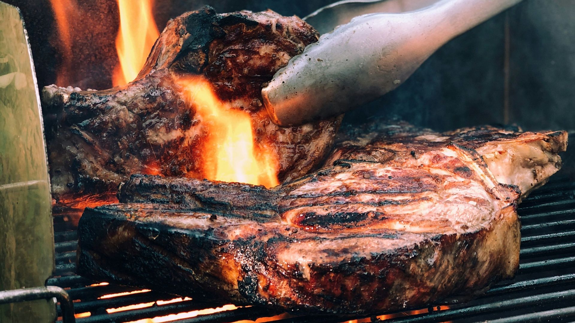 gray metal tong and grilled meat with fire