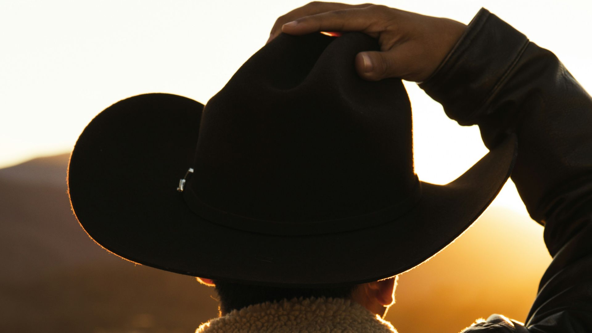 a person wearing a cowboy hat and jacket