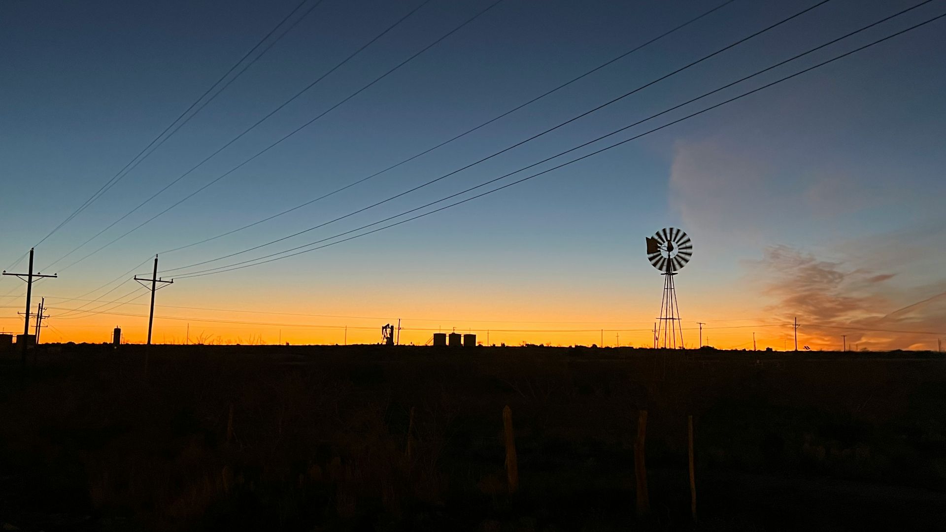 a windmill in the distance with power lines in the foreground