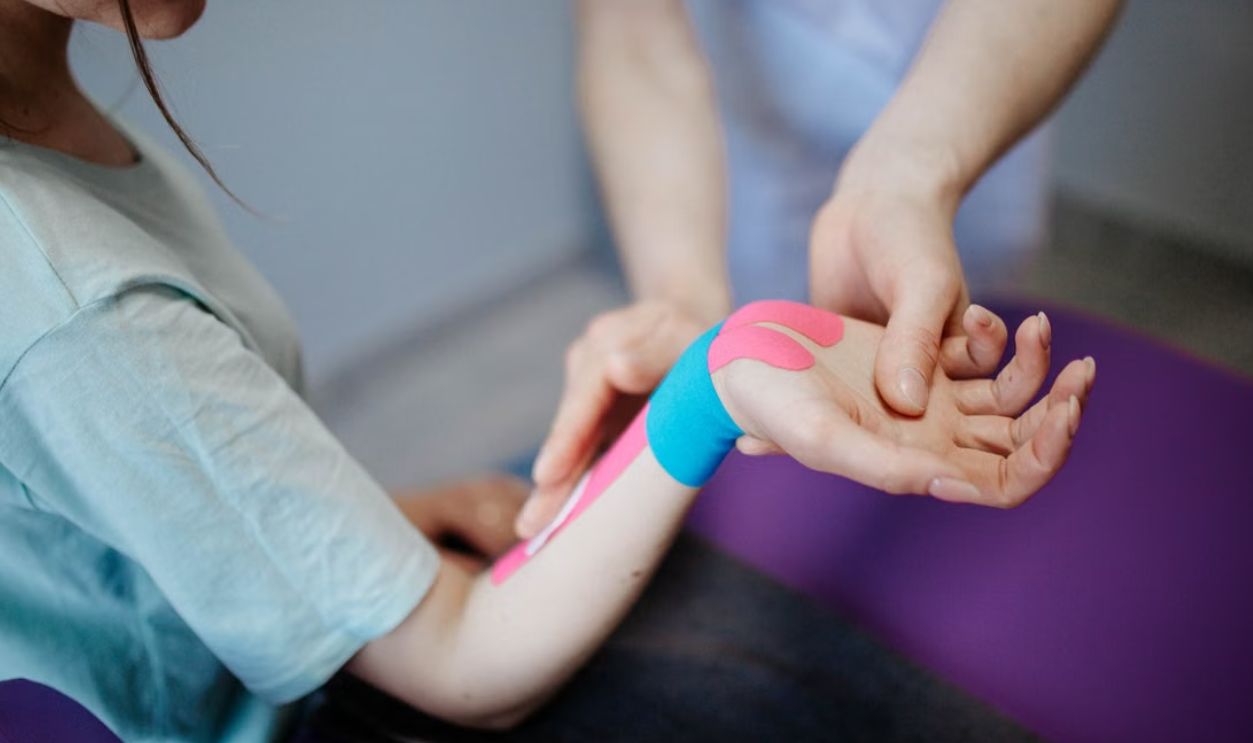 Close-up of a therapist applying kinesio tape for pain relief during a therapy session