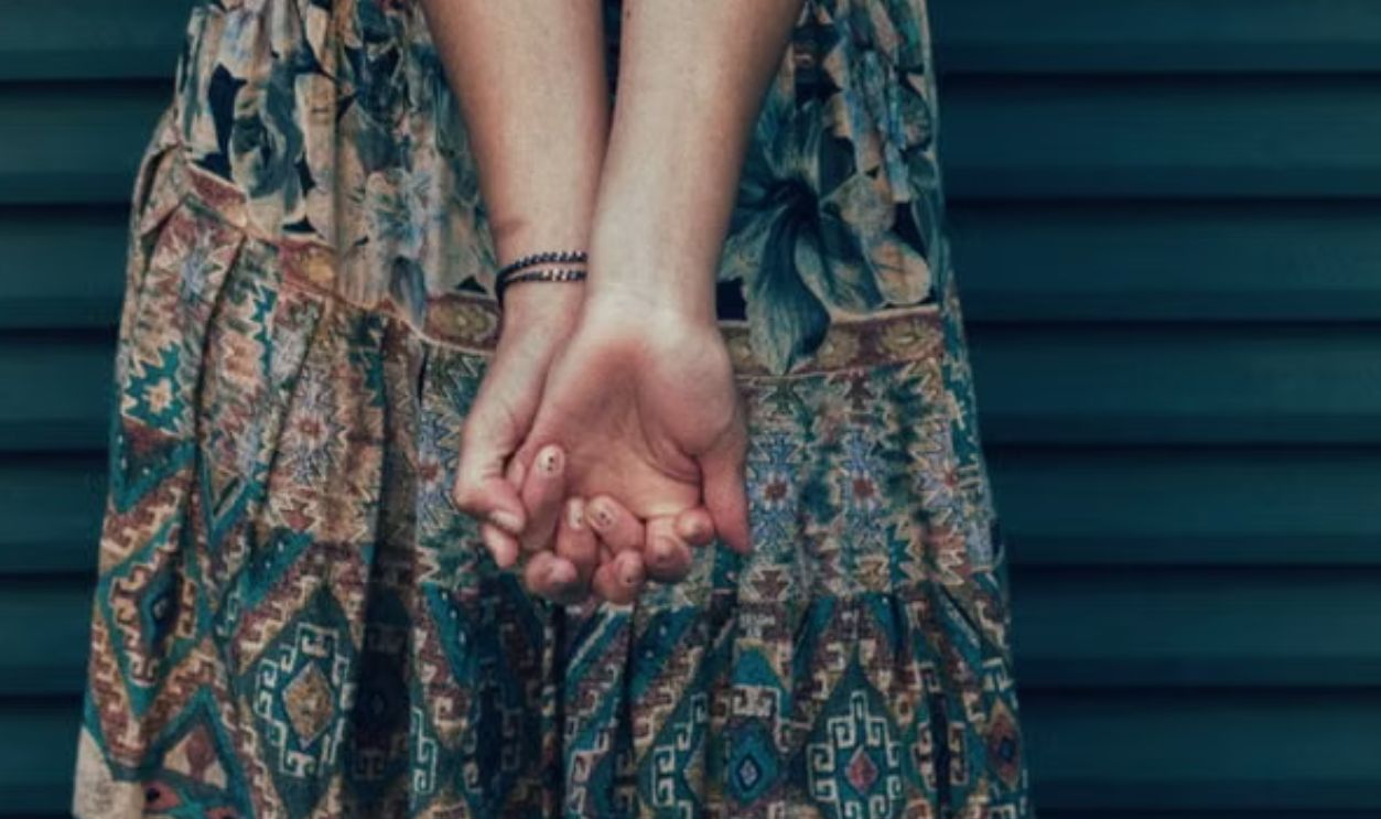 Woman in a bohemian skirt showing a unique wrist tattoo outdoors