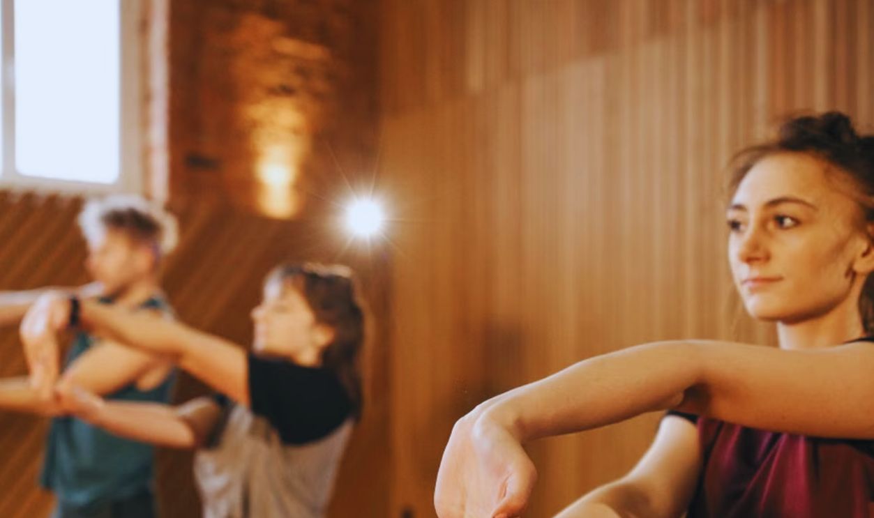 Individuals stretching during a fitness class in a gym setting, promoting group exercise.
