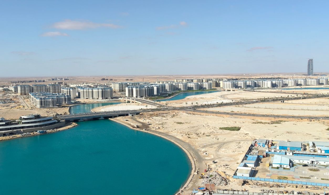Aerial view of modern residential buildings stretching along an artificial lake with vibrant turquoise waters in New Alamein City. Photographed in El Alamein City, Egypt, on October 1, 2025