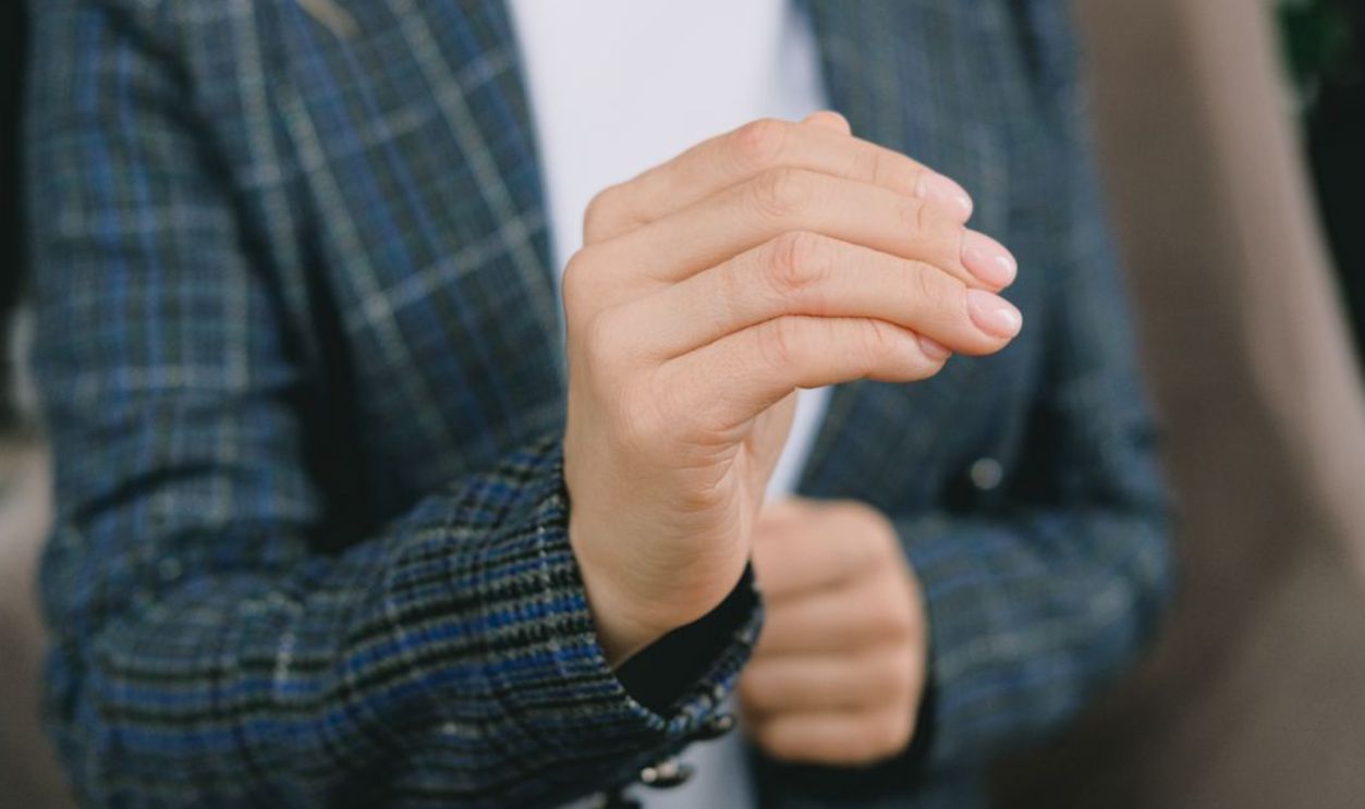 Close-up of a woman's hand gesturing in sign language indoors
