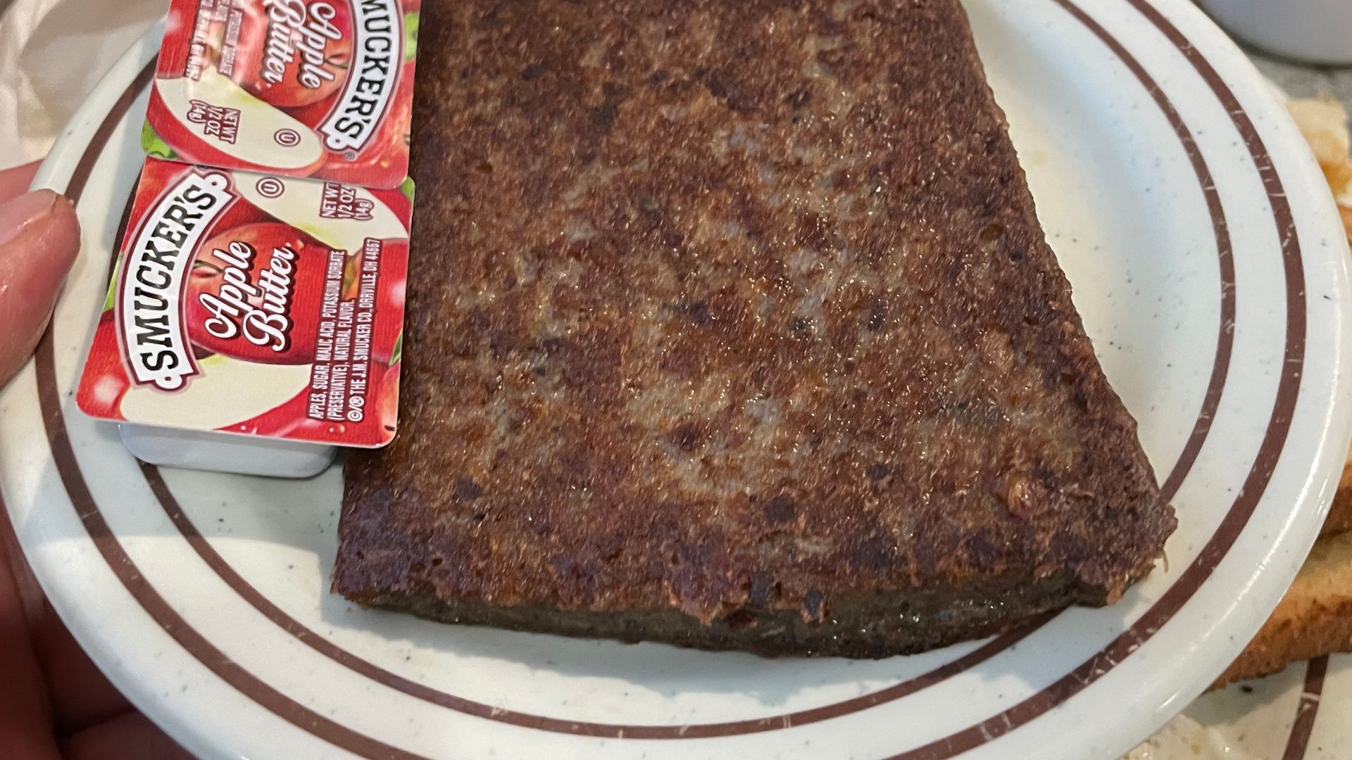 Scrapple slice with two Smuckers Apple Butter portion cups at Airport Diner, Kutztown, Pennsylvania (2025-11-26)