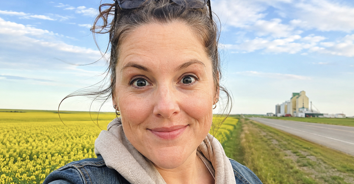 smiling woman with a bun, sunny day, Canadian prairies in the background.