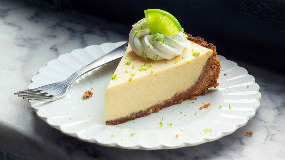 Slice of Key Lime Pie with Whipped Cream and Lime Zest on a Plate