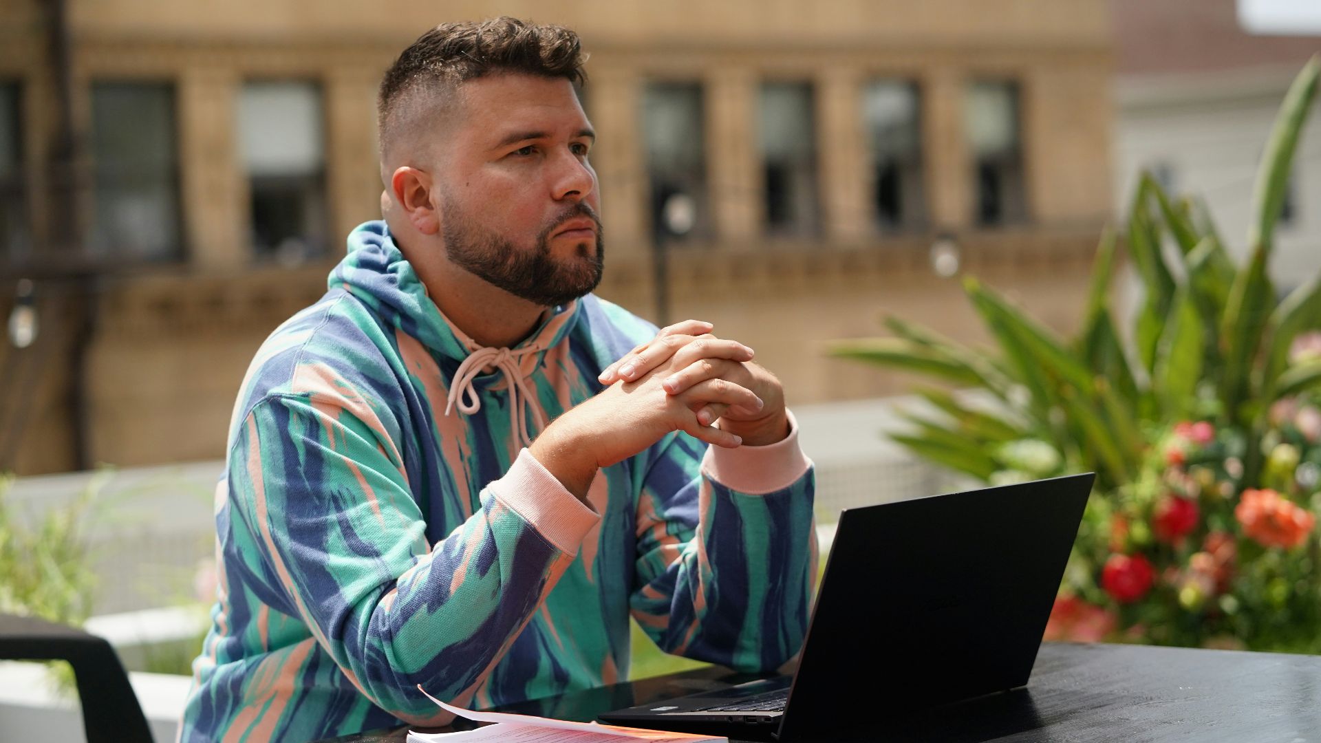 man in blue and white tribal print hoodie sitting beside black laptop computer
