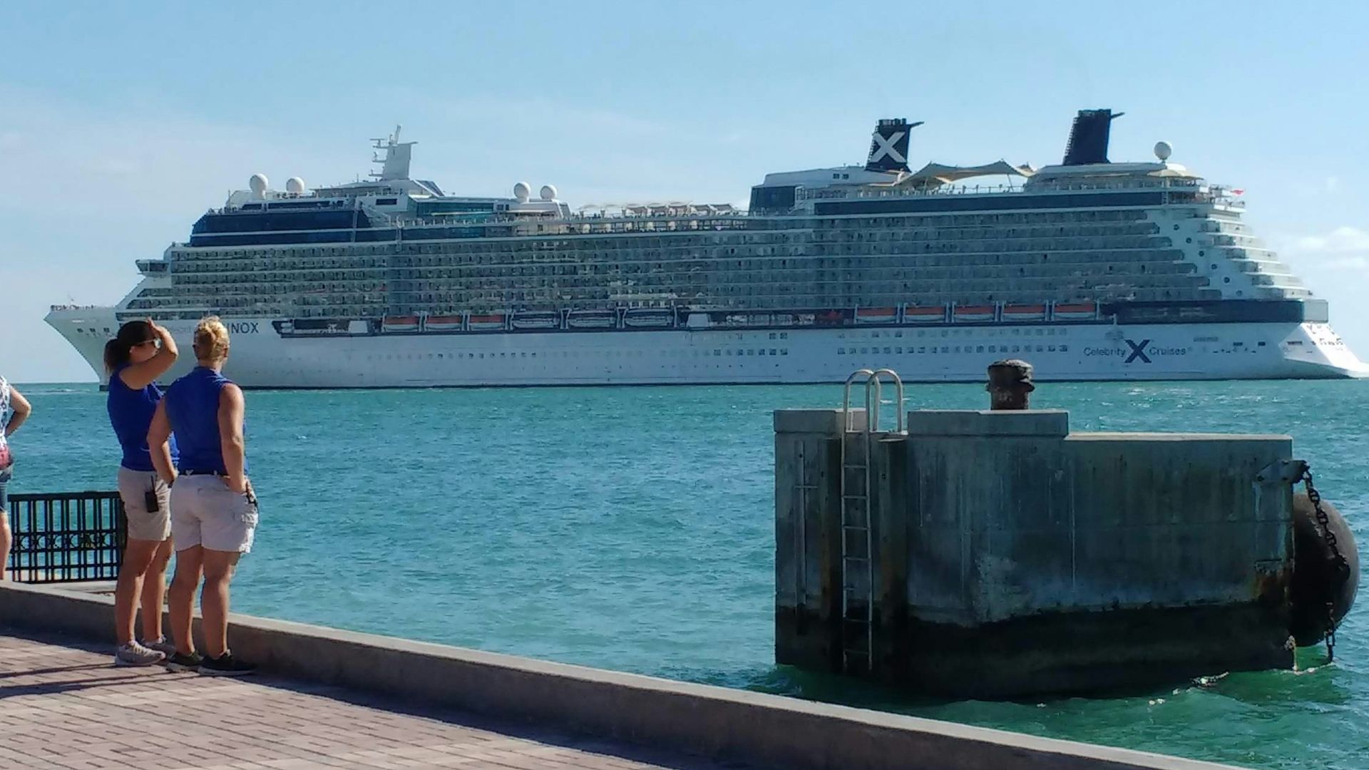 2 person standing across white cruise ship on body of water