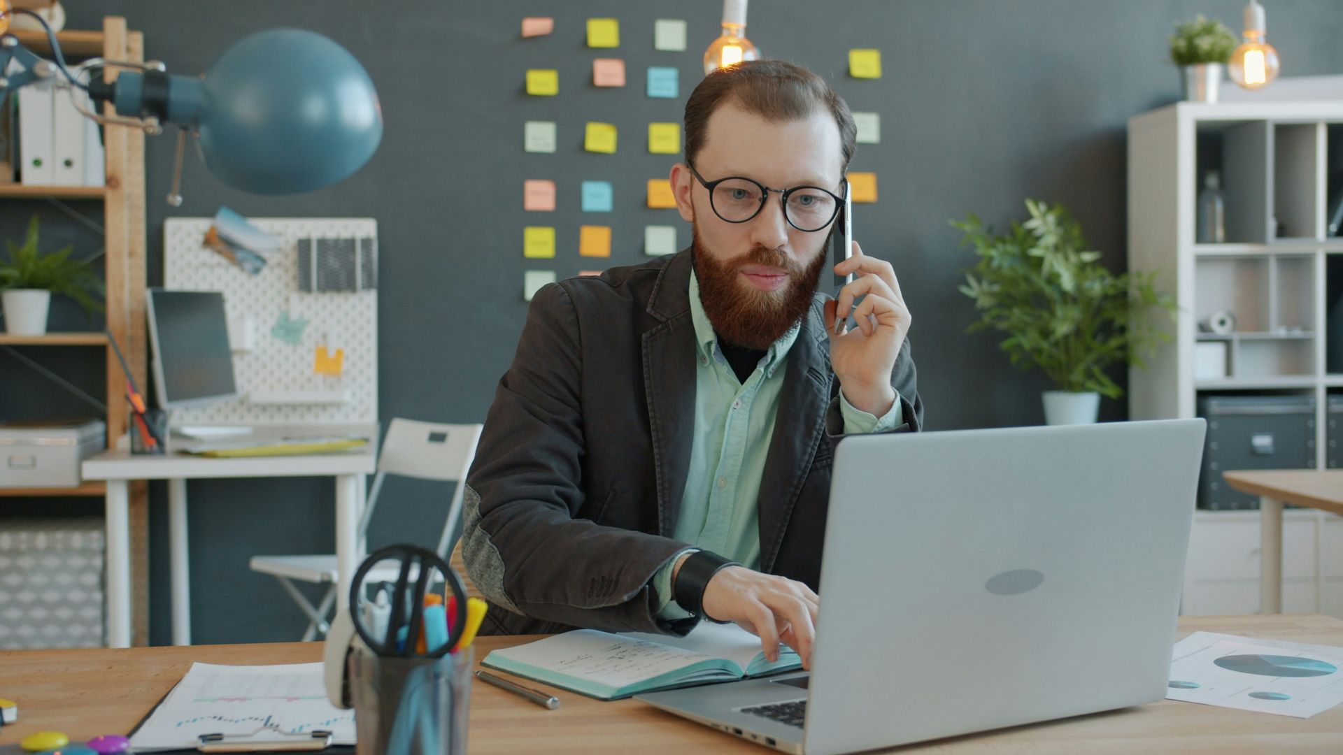 Man on phone working on laptop in office