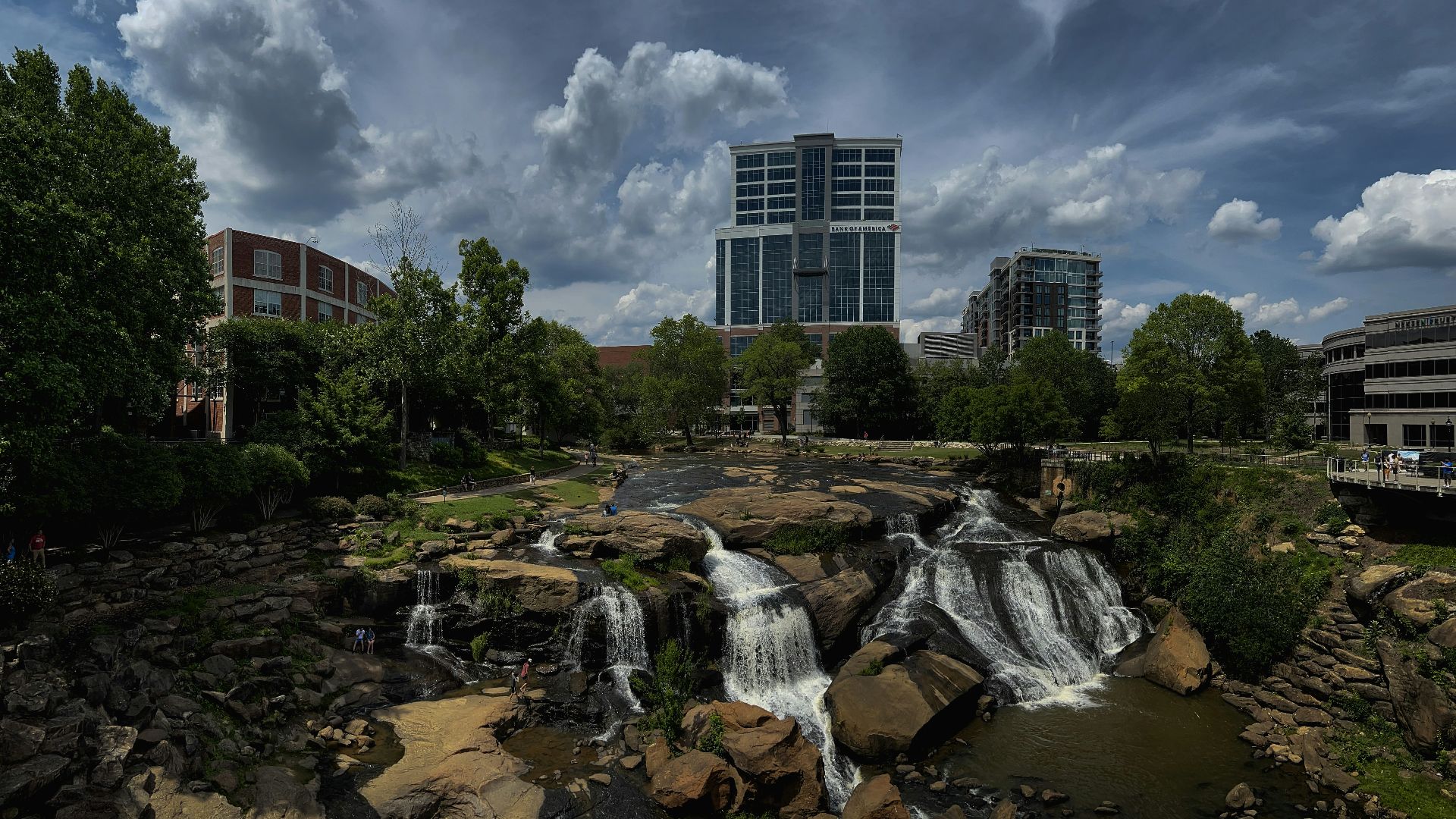 a waterfall in the middle of a river with a city in the background