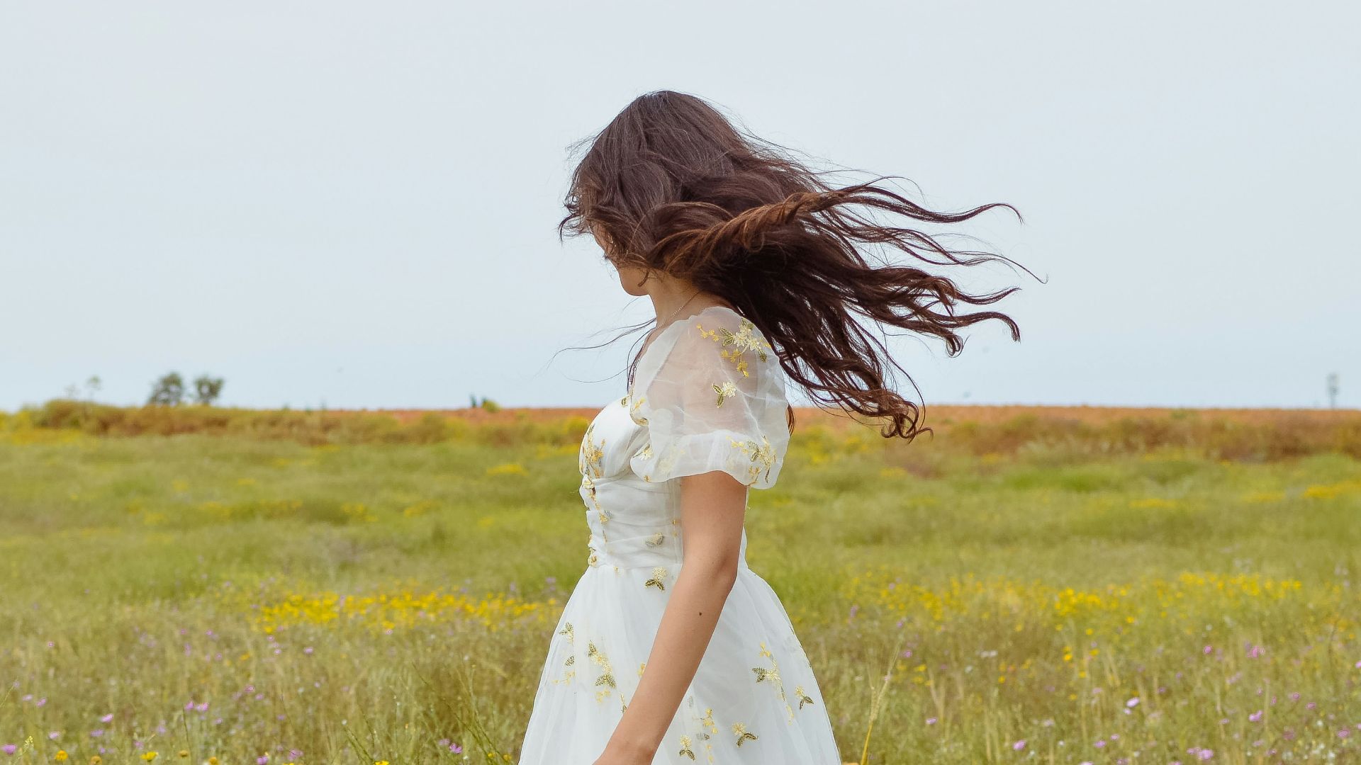 Woman in white dress with hair blowing in a field