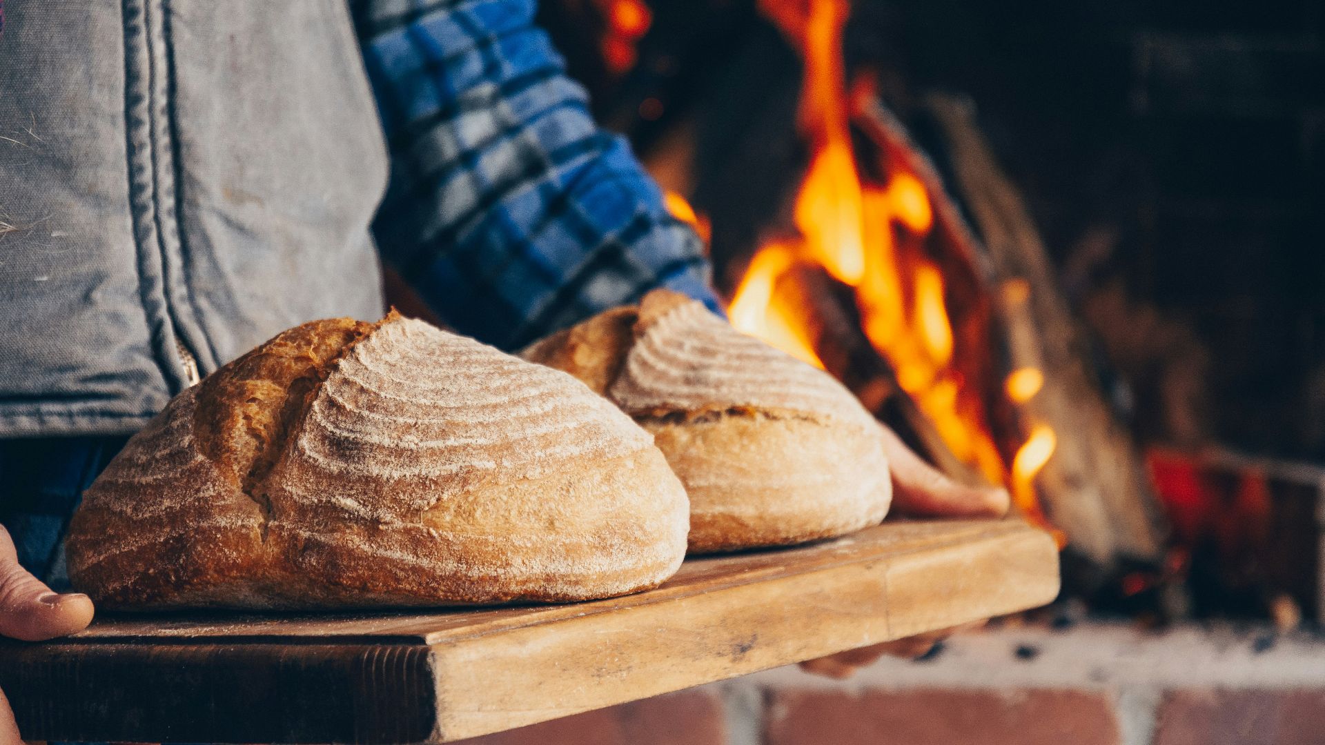 person in blue and white plaid long sleeve shirt holding bread