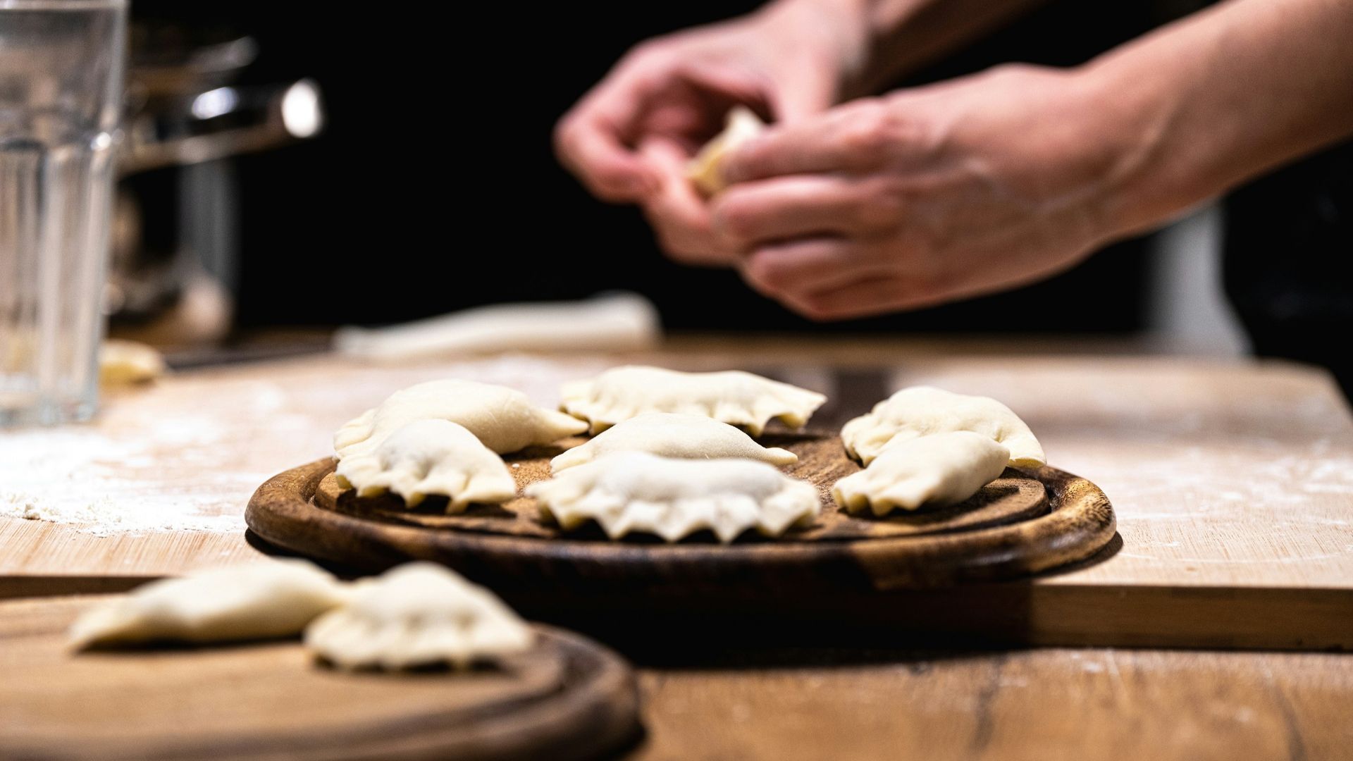 A person preparing dumplings on a wooden table