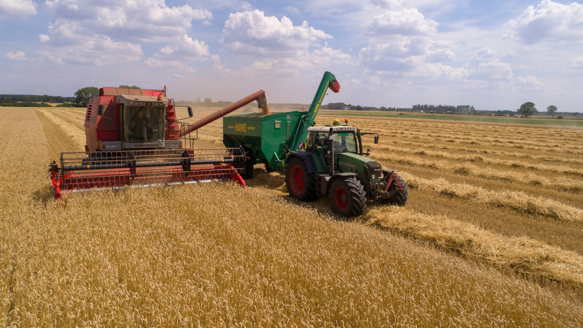 two green and red cultivators on brown field