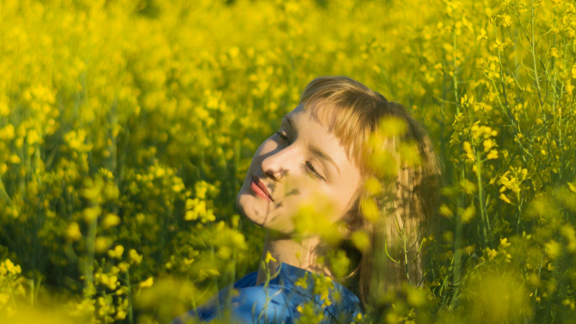 girl in blue floral dress standing on yellow flower field during daytime