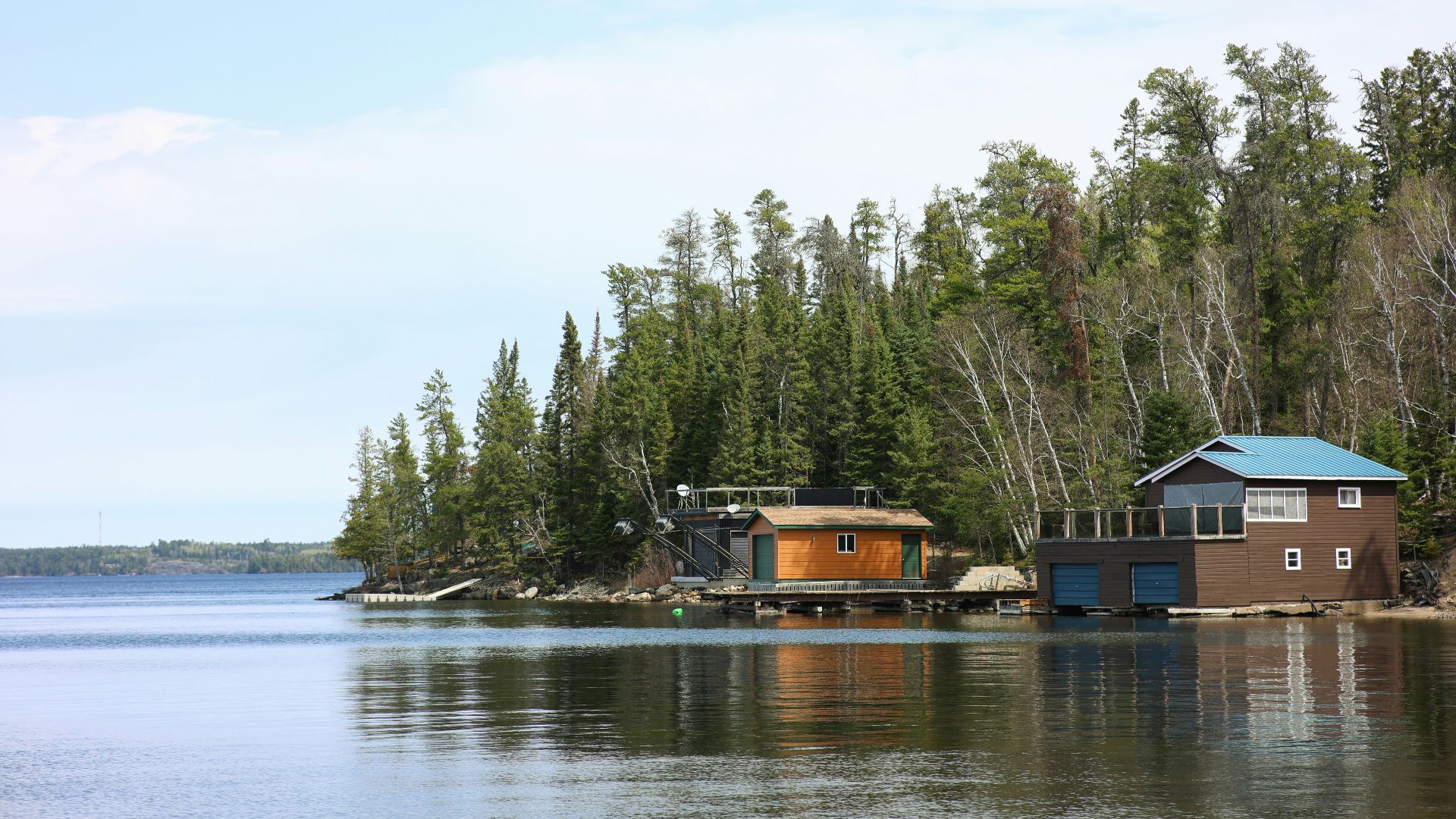Lakeside cabins sit next to a forested shoreline