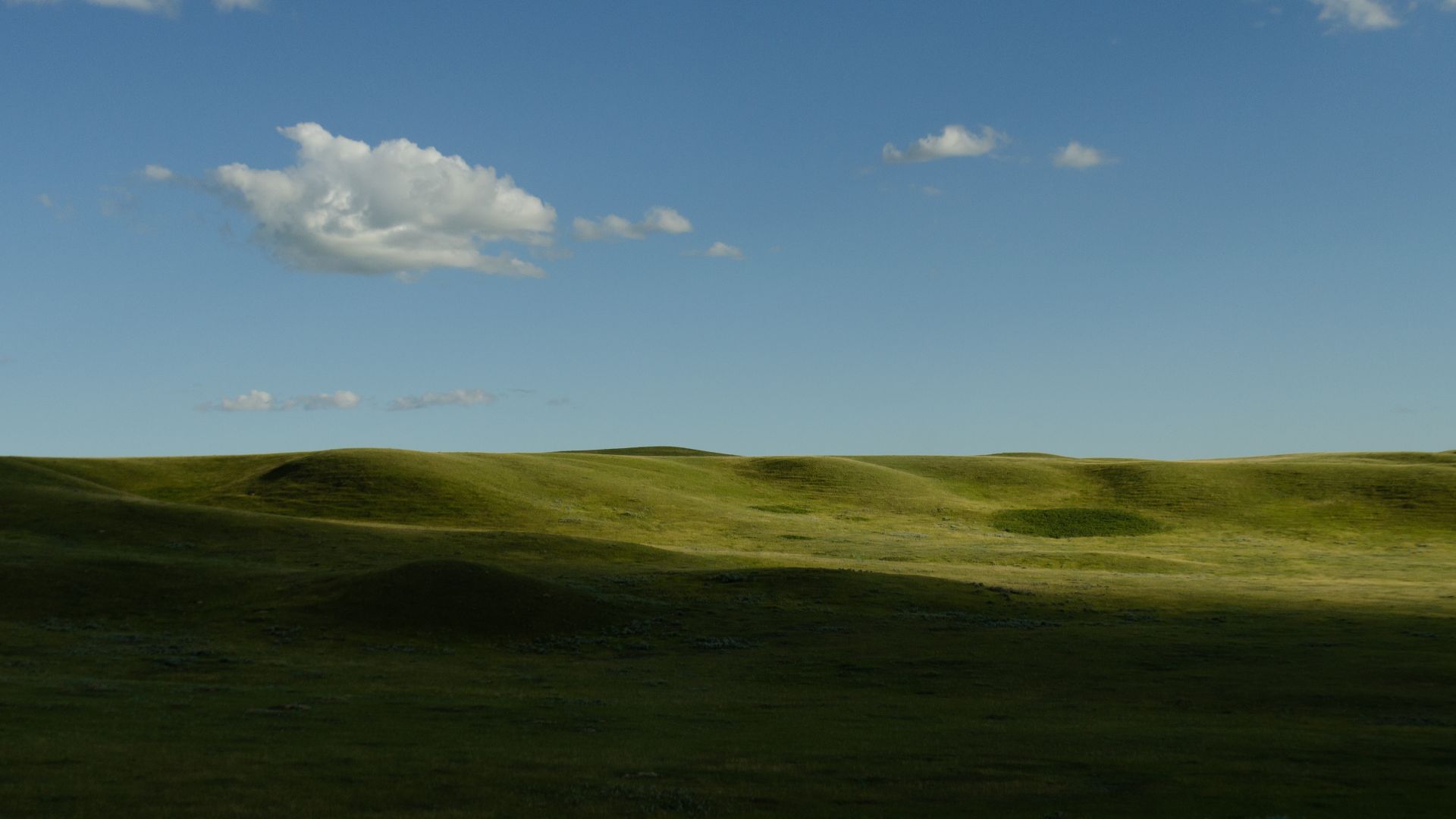 The shadow of a cloud lies over the grassy hills of Grasslands National Park, Saskatchewan.