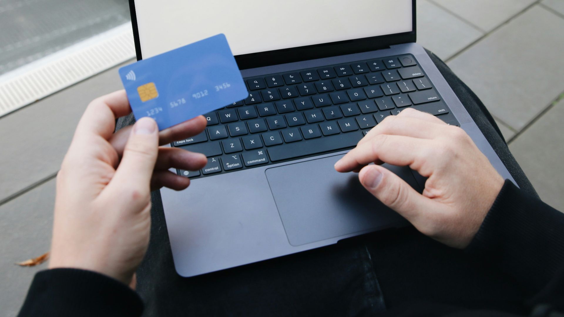 A person sitting in a chair with a laptop and a credit card