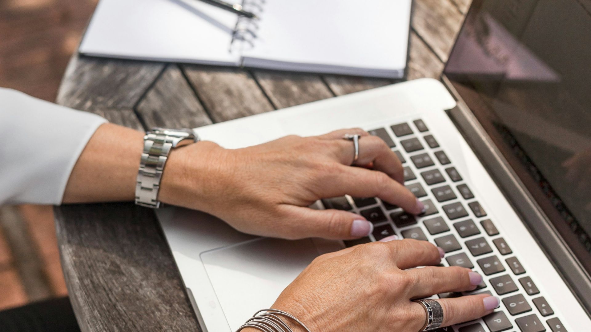 person typing on MacBook Pro on brown wooden table during daytime photo