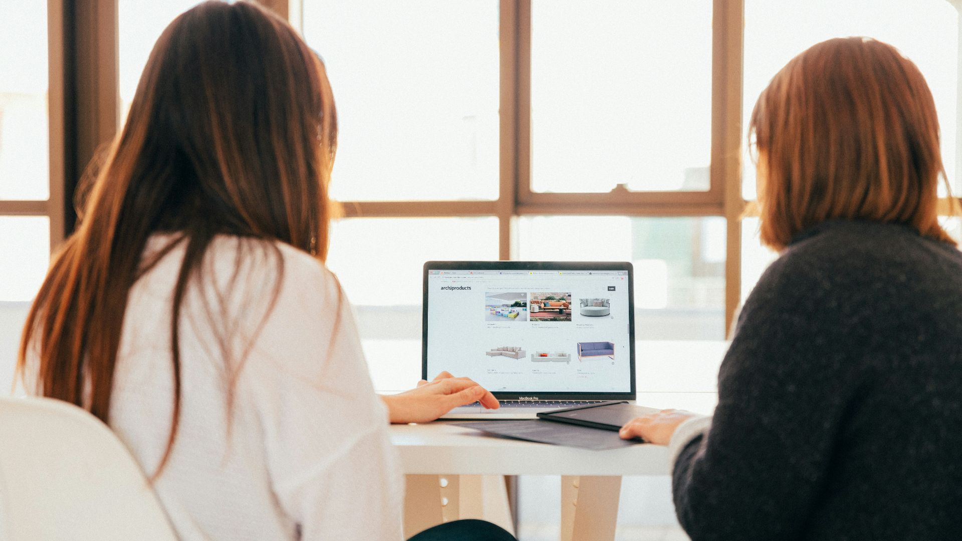 two women talking while looking at laptop computer