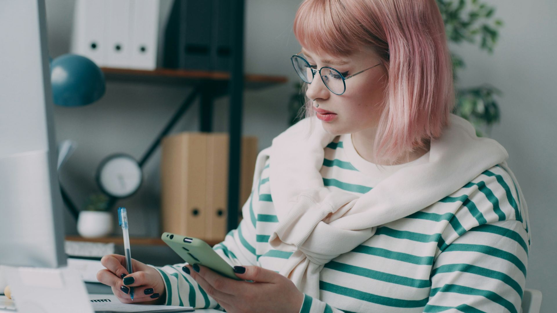 A woman sitting at a desk using a cell phone