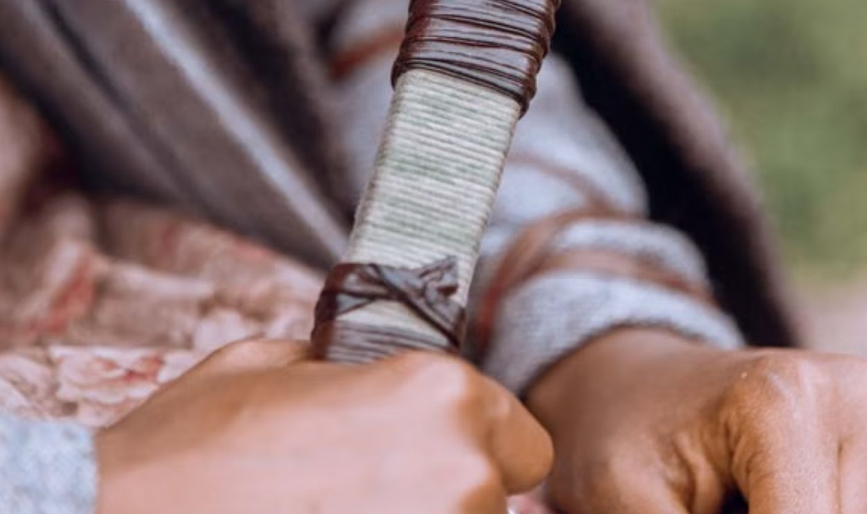 Close-up of skilled artisan weaving with natural yarn, emphasizing traditional craft techniques