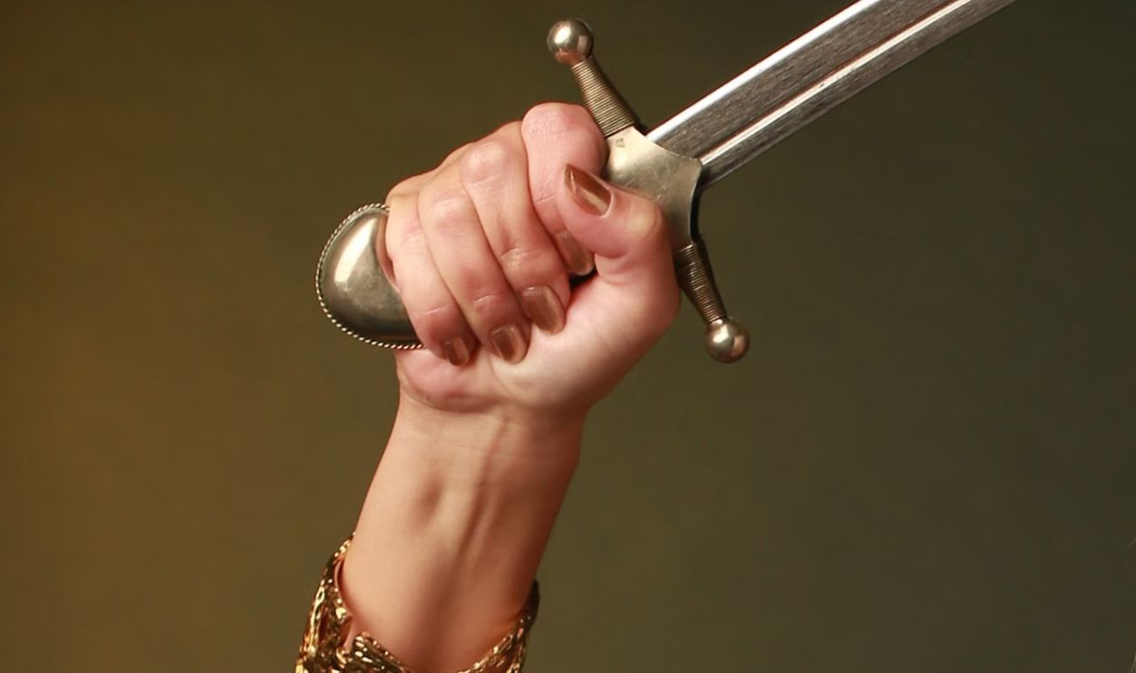 Stunning portrait of a woman in a red dress holding a dagger, showcasing fashion and jewelry